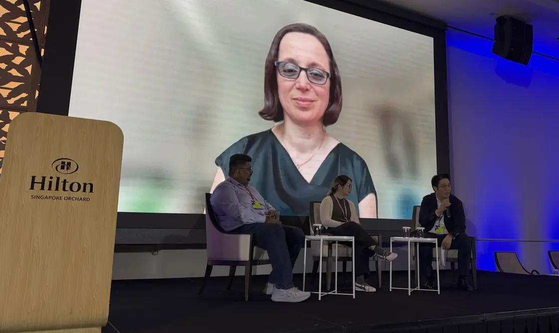 The panel on stage at Hilton Singapore Orchard, with the fourth panellist joining by video on the screen behind.